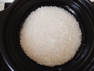 腊肠煲仔饭,把泡好的米和水倒入刷好油的砂锅中。水开后立刻转小火，煮到水分基本收干。
