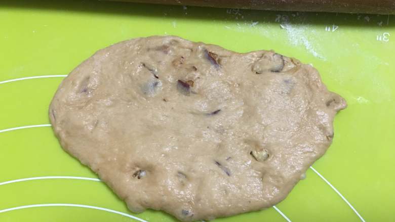 红枣面包,用擀面棍将面团擀成椭圆形，如果面团稍微湿，可以撒少许干粉