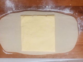 美味蝴蝶酥,松弛好的面团擀成片状黄油的两倍大，把黄油包裹起来。