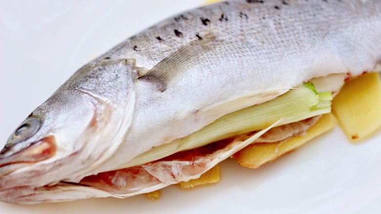 香辣酱蒸鲈鱼,把洗净的鲈鱼放入蒸盘中，鱼肚子里先塞满葱白，这样既可以去腥味，又不会让鱼在蒸制的过程中变形。