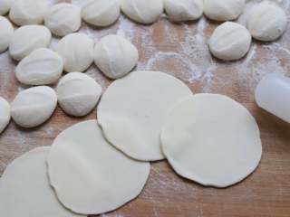 玫瑰花煎饺,往面剂子上撒上一层干面粉放粘，然后用掌心压扁，再用擀面杖擀成圆形的饺子皮。