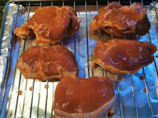 蜜汁叉烧肉（烤箱版）,肉依次摆好，放在烤架上，盆里会有酱汁残留，刷在表面上，再刷一层蜂蜜