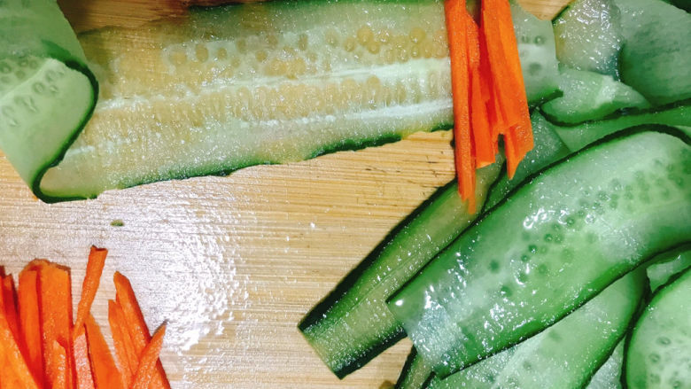 凉拌黄瓜卷,取几条胡萝卜丝放在青瓜薄片上。