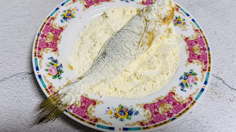 酥炸小黄鱼,将腌制好的小黄鱼两面均匀地裹上一层薄薄的的面粉