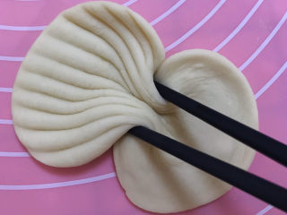 香甜贝壳馒头,接着用筷子夹紧中间部位提起来。