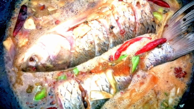 炖草鱼,把腌制好的鱼和料汤一起入锅中。