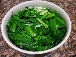 韭菜炒豆腐,将韭菜拆洗干净切成小段并用盐水泡一会儿再捞出沥干水分。