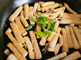 韭菜炒豆腐,豆腐煎好后放入葱姜，翻炒出香味。