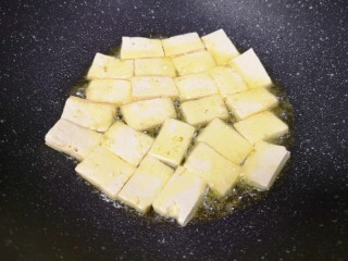 韭菜炒豆腐,炒锅内倒适量的食用油烧热，下入豆腐块中火煎制。