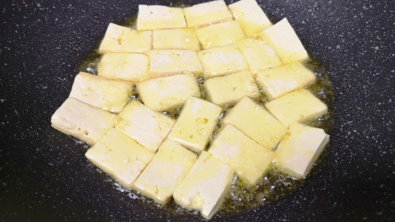 韭菜炒豆腐,炒锅内倒适量的食用油烧热，下入豆腐块中火煎制。
