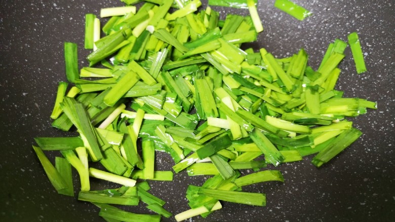 韭菜炒豆腐,将煎豆腐剩余的油继续加热，下入韭菜翻炒至变色。