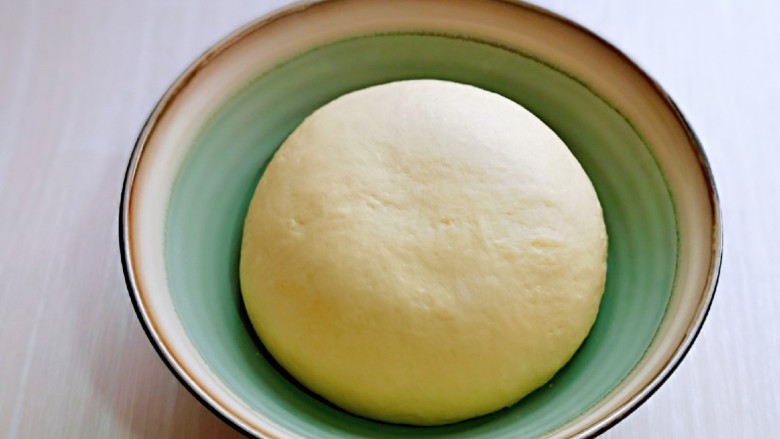 菠萝面包,将面团取出揉圆，放入器具中，盖上保鲜膜进行发酵。(注意保持面团的湿度)