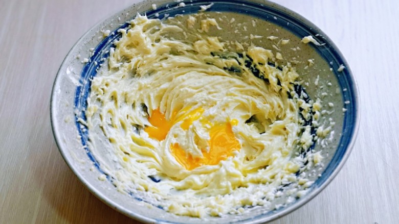 菠萝面包,待黄油蓬松的状态时加入一半的蛋液，电动打蛋器低速打至均匀。