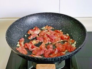 蒜苔炒牛肉,起油锅，加入腌制好的牛肉片煸炒。