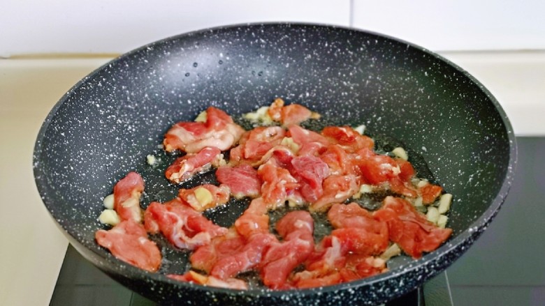 蒜苔炒牛肉,起油锅，加入腌制好的牛肉片煸炒。