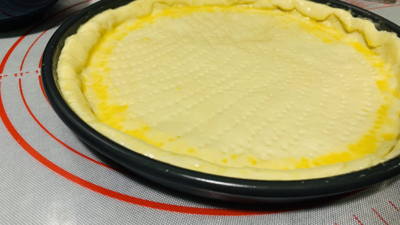 芒果披萨,在披萨胚的边缘涂上全蛋液；