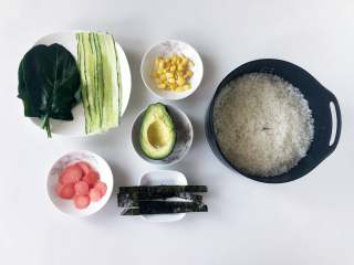 玲珑可爱的手鞠寿司，吃一口满满的幸福感,蒸米饭的时候，把配料准备好。黄瓜用刮皮刀削成长条，玉米剥好，水果胡萝卜和牛油果去皮切成薄片，海苔剪成长条。