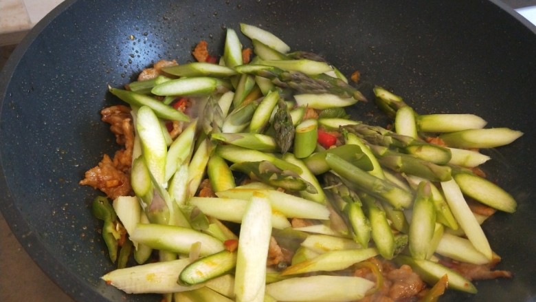 芦笋炒肉片,倒入青红椒炒均匀倒入芦笋。