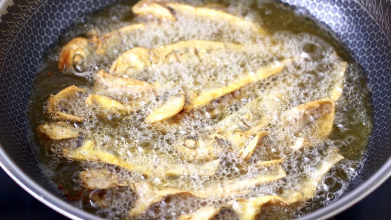 香脆椒干煸黄花鱼,锅烧热倒入能漫过黄花鱼的花生油烧热，把黄花鱼放到锅里开始炸至。