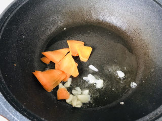 菠菜木耳炒鸡蛋,锅中倒入底油，炒香蒜片和胡萝卜片；
