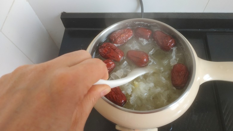 苹果银耳红枣汤,用勺子搅拌至冰糖融化