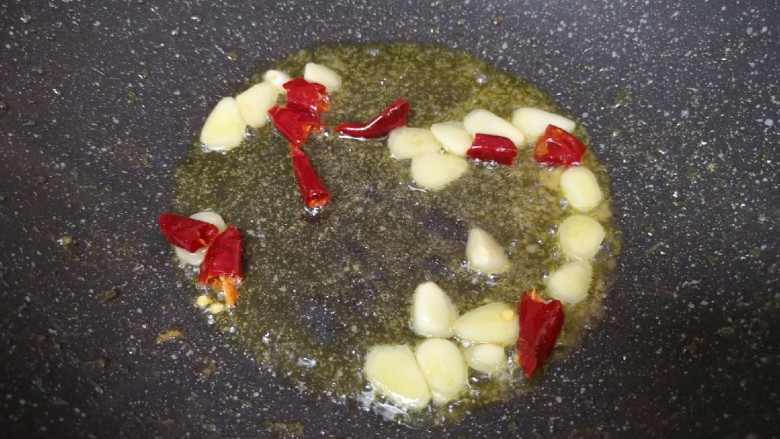 莴笋炒虾仁,锅底留余油继续烧热，下入蒜片和干红辣椒炒香。