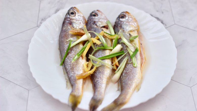 豆皮黄花鱼,这个时候在黄花鱼身上撒上葱姜丝，用手抓匀腌制10分钟左右。
