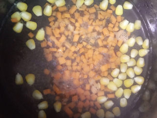 咖喱煎米饼,烧开水，将玉米和胡萝卜放入锅中煮熟