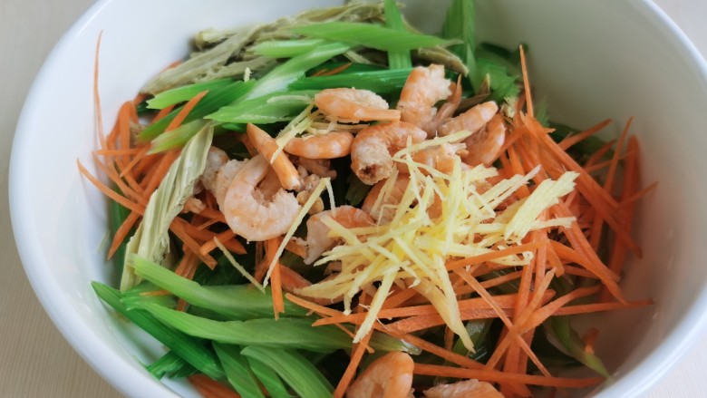 芹菜拌腐竹,把腐竹、芹菜、胡萝卜、海米以及姜丝放到一个大碗里混合。