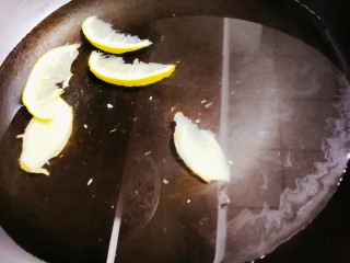 爆炒田螺肉,锅中加水，放入柠檬和姜片，再倒入一勺料酒