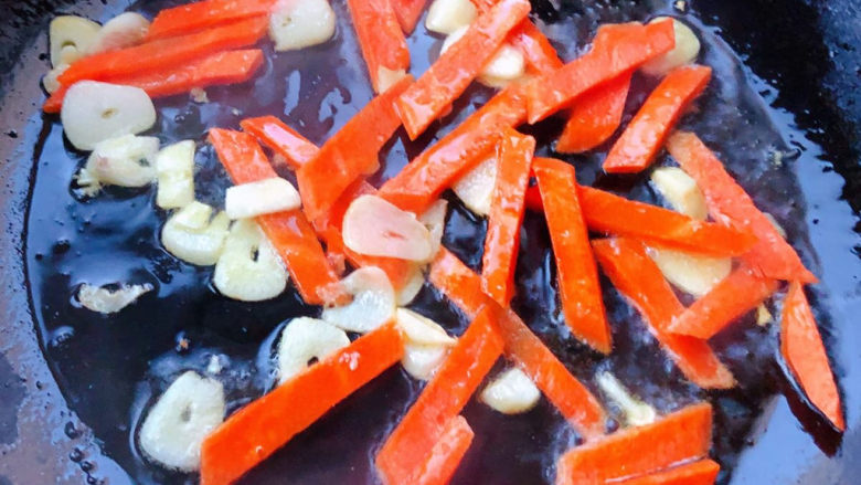 牛肉丝炒芹菜,锅中倒入底油加热放入蒜片爆香再放入胡萝卜炒至变色