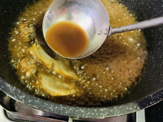 酱焖黄花鱼,中间翻开锅盖，用勺子舀汤汁浇上；
