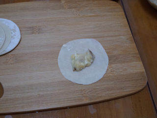 饺子皮变身🍌 香蕉派,饺子皮用擀面杖稍微擀薄一些，不擀直接包也是可以的。把香蕉碎放在饺子皮中间。