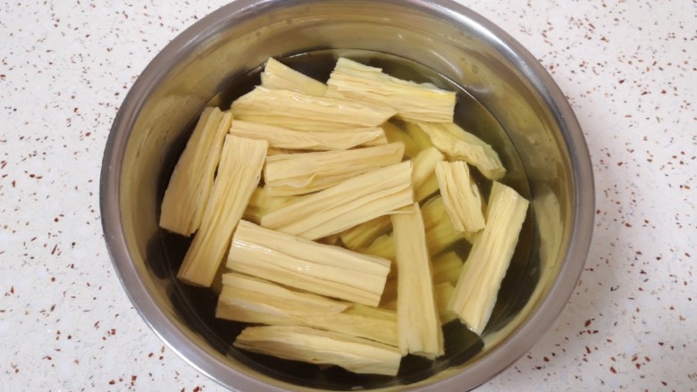 芹菜拌腐竹,干腐竹掰成段放入温水里面，加一点点盐泡软。