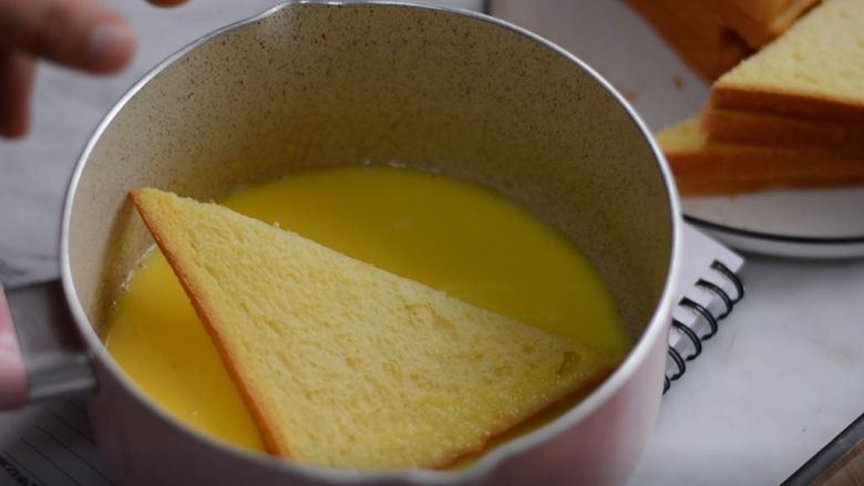 香酥面包片——秒杀面包店的面包片配方,将面包片放入汤汁中，正反面沾满后放入烤盘。
