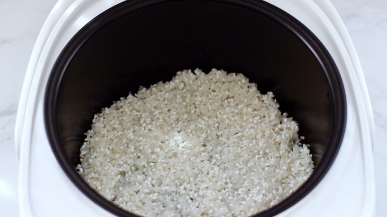三色藜麦青菜饭团,浸泡好的大米和糯米放入电饭煲中。