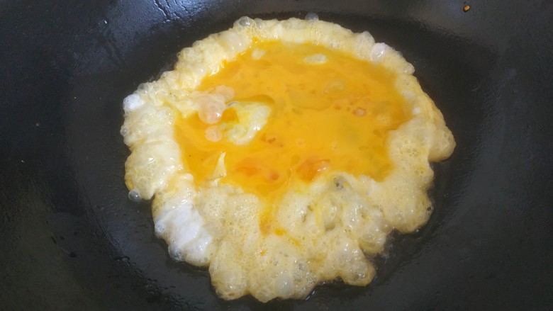 大头菜蛋炒饭,锅中放入适量植物油。放入蛋液煎至凝固成形