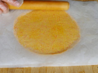 胡萝卜饼干,取出面团，把冷藏好的面团放在2张吸油纸中间擀成0.4cm左右的的薄片，上下面都要擀几下，让面团受力均匀，也可以撒一些芝麻在饼干胚上，烤出来的饼干非常香。