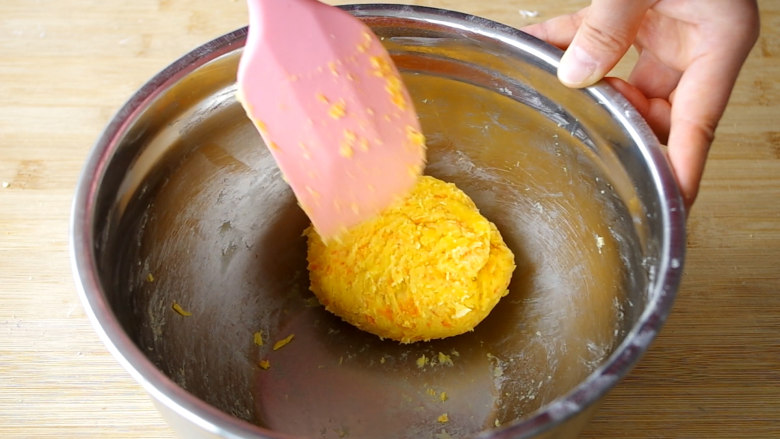 胡萝卜饼干,分2次加入面粉，用刮刀翻拌均匀至无干粉，形成面团，面团表面不用太光滑。