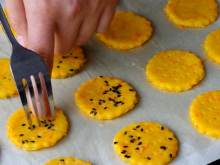 胡萝卜饼干,烤盘铺上吸油纸，把做好的饼干胚移至烤盘上，用叉子戳出小孔，可以防止饼干在烤制中鼓包。