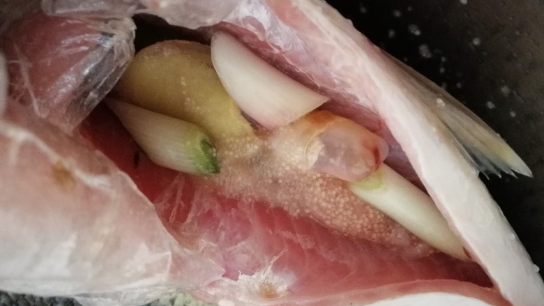 煎焖开江鱼,把姜片和葱段塞进鱼肚里。
