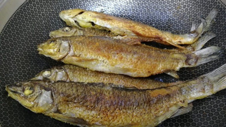 煎焖开江鱼,把之前煎好的鱼都放入锅内。