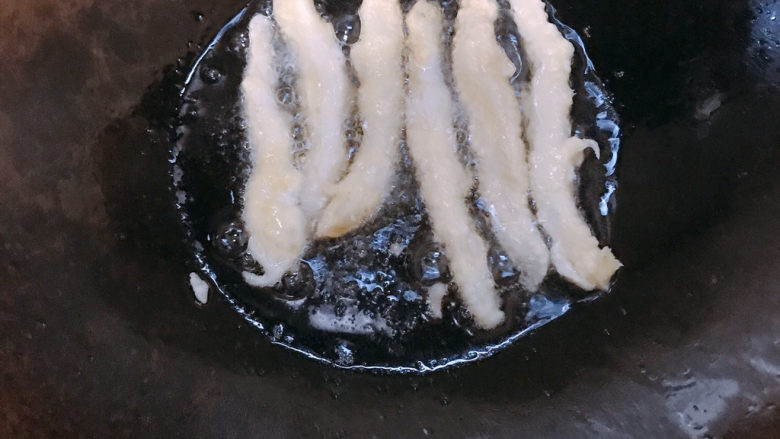 炸银鱼,油烧至6成热。把挂好浆的银鱼一条一条放进油锅。