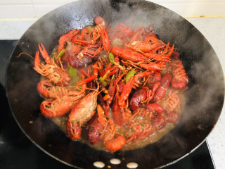 蒜香小龙虾,中火慢慢翻炒均匀，让汤汁裹上小龙虾。