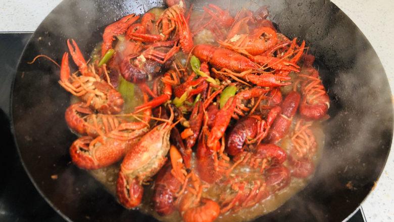 蒜香小龙虾,中火慢慢翻炒均匀，让汤汁裹上小龙虾。