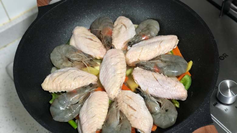 0厨艺也能做！好吃到爆炸的虾翅焖锅,将腌渍好的鸡翅和虾码在蔬菜表面；