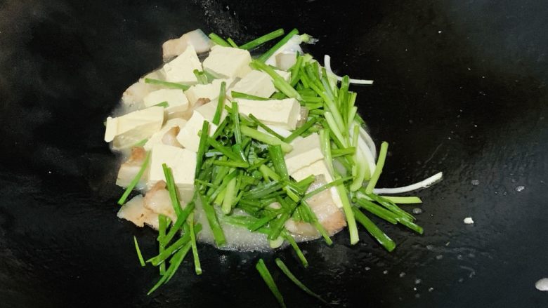 猪肉炒豆腐,翻炒均匀后加入葱段。