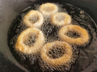 黄金鱿鱼圈,锅里油热后放入鱿鱼圈炸制。