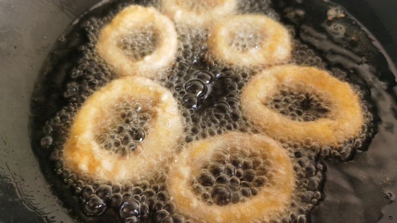 黄金鱿鱼圈,锅里油热后放入鱿鱼圈炸制。