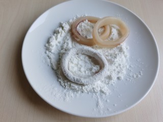黄金鱿鱼圈,盘中放些淀粉，将鱿鱼圈均匀的沾上一层淀粉。